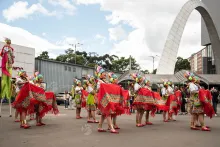 A group of women dancers wearing clothing from a Colombian indigenous culture. They wear colorful skirts and colorful fique hats.