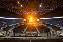 Inside the arena, showing empty stands and a beam of bright golden light emanating from the stage.
