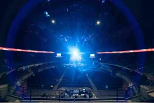 Inside the arena, showing empty stands and a beam of bright blue light emanating from the stage.