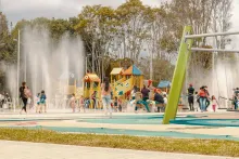 Children playing in the water in a park, laughing and enjoying a sunny day.
