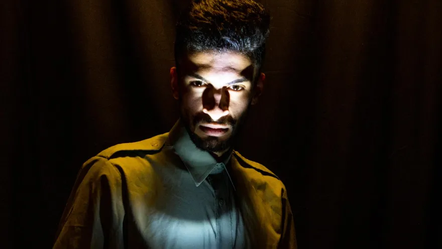 Barraca Teatro hombre jóven actor en primer plano a oscuras con una luz de vela que le ilumina el rostro. 