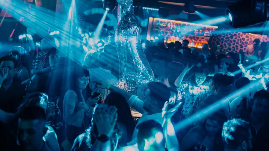 Disco Jaguar al interior un salón oscuro con una figura de jaguar brillante y personas iluminadas con luces azules.