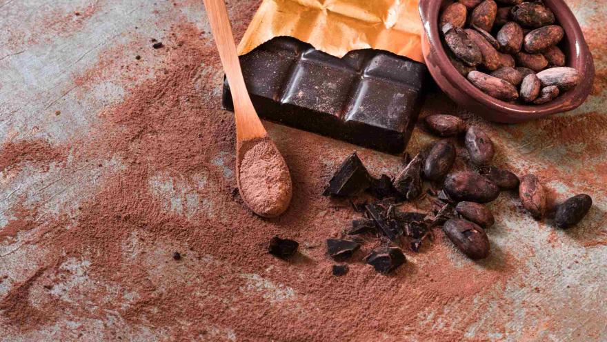 Mesa con residuos y trozos de chocolate. Hay una cuchara negra con chocolate molido.
