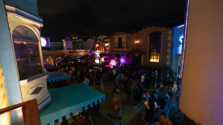 Theatron - internal square at night, featuring iconic castle-like facades, and people talking.
