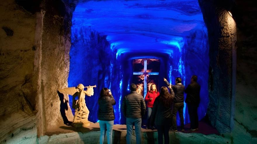 Catedral de Sal de Zipaquirá y turistas tomando fotos en el interior de la cueva del ángel y el fondo azul.