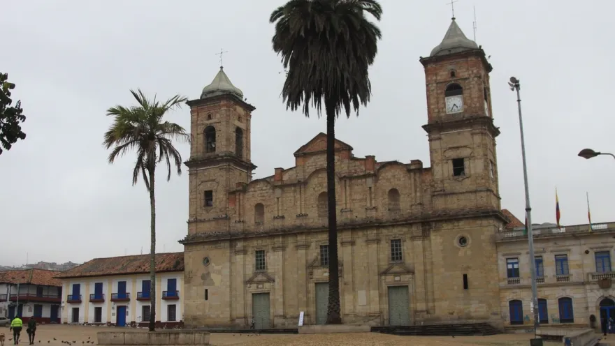  Catedral Santísima Trinidad y San Antonio de Padua, fachada frente de día cielo gris y un par de palmas a los costados. Dos personas caminan al frente.