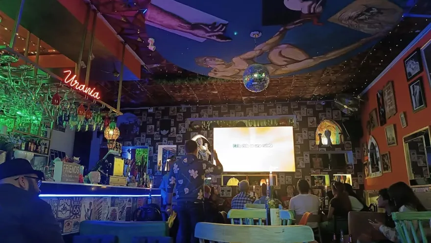 Inside Brokeback Mountain decorated interior with colorful photos and painted walls.  People talking and watching a screen
