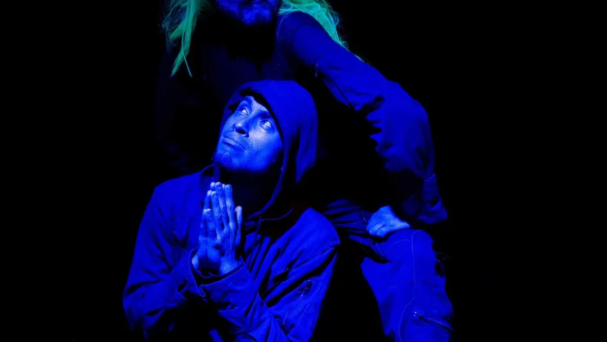  Barraca Teatro con actores en escena arrodillados miran de frente. Uno tiena una peluca amarilla.