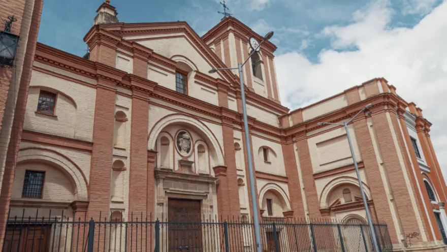  Iglesia San Ignacio de Loyola, fachada completa en la drillo y pintura amarilla en la que se ven ocho ventanas y cuatro puertas. En la torre más alta se observa el reloj.