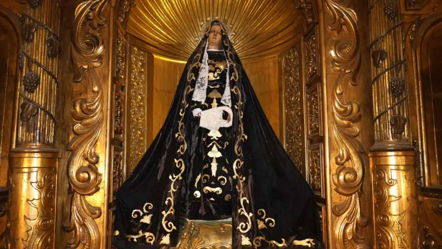 Iglesia de La Veracruz con la figura de la Vírgen vestida de negro en primer plano y que reposa dentro de un retablo tallado.