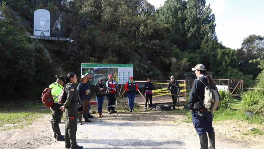 Guia turístico da orientaciones a grupo de visitantes que hacen el camino por el sendero Guadalupe - Aguanoso. Dos agentes de policía observan.