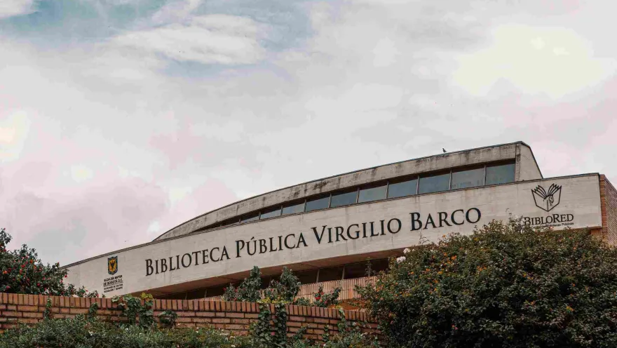 Brick and stone facade prominently displaying the name of the Virgilio Barco Library. The sky is gray.
