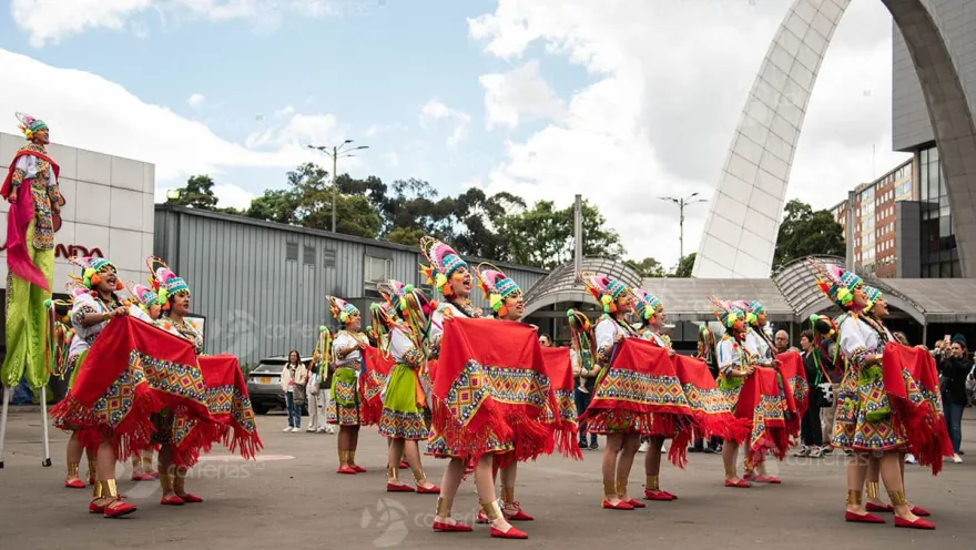A group of women dancers wearing clothing from a Colombian indigenous culture. They wear colorful skirts and colorful fique hats.