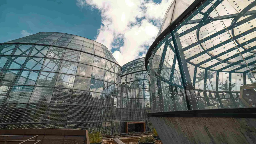Six gigantic glass structures in the shape of vaults. The sky is cloudy.