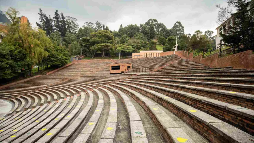 Oval-shaped brick gallery or grandstand surrounded by leafy trees.