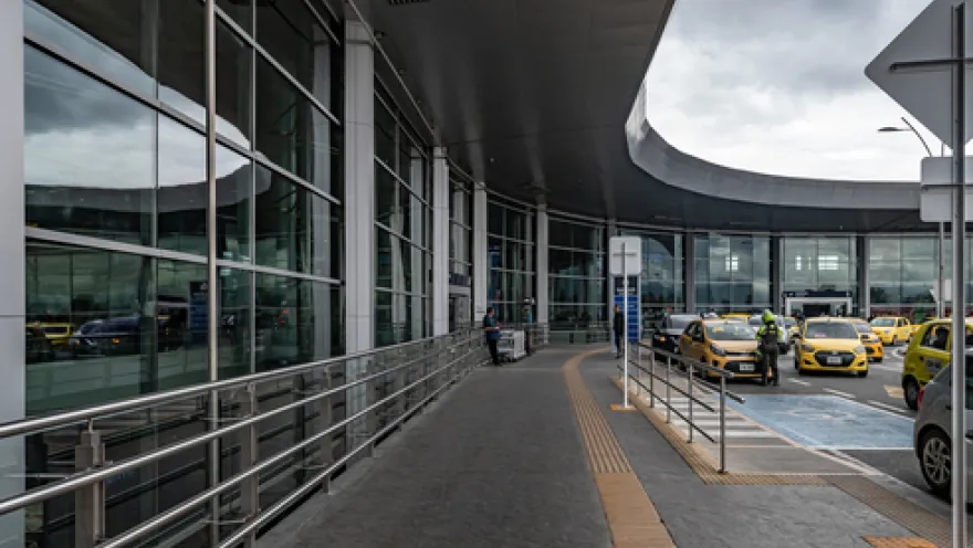 Exterior of a building with many windows. Several taxis are parked in front.