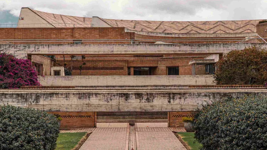 Structure with brick and concrete walls and floor. Several flowers and plants grow along the sides.