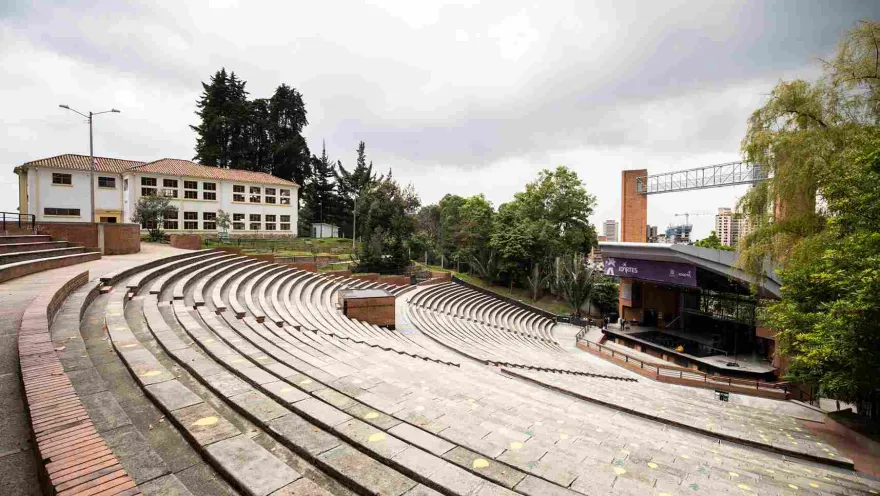 Oval-shaped brick gallery or grandstand. In the background, an old, two-story, white building is visible.