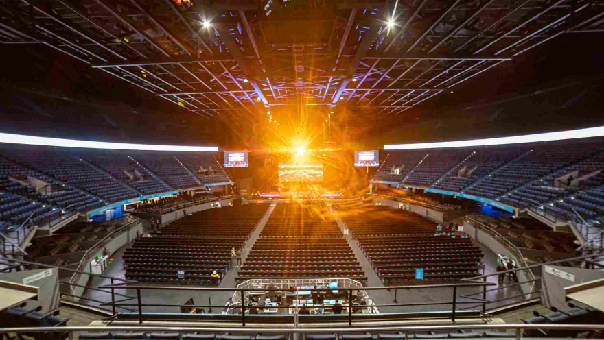 Inside the arena, showing empty stands and a beam of bright golden light emanating from the stage.