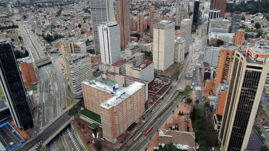 A daytime view from the observation deck looking down, showing Calle 26 and Carrera Séptima with several buildings, including the Hotel Tequendama.