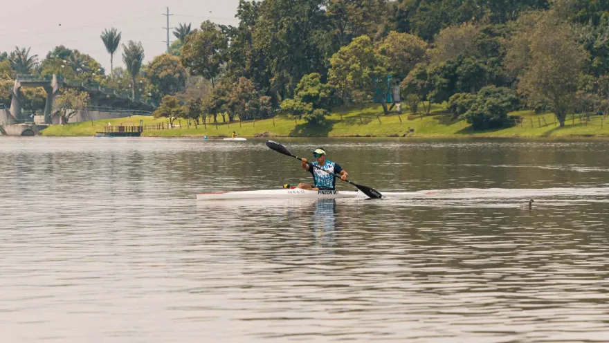 Simón Bolívar Park with a kayaker paddling on the lake. The man, wearing athletic clothing, moves his paddle.