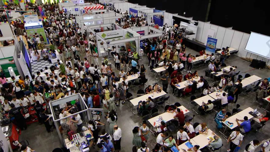 A hall with several booths crowded with people, seen from above.