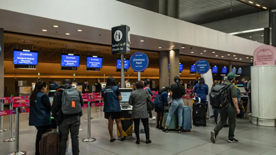 Interior of an airport showing some people walking with suitcases.