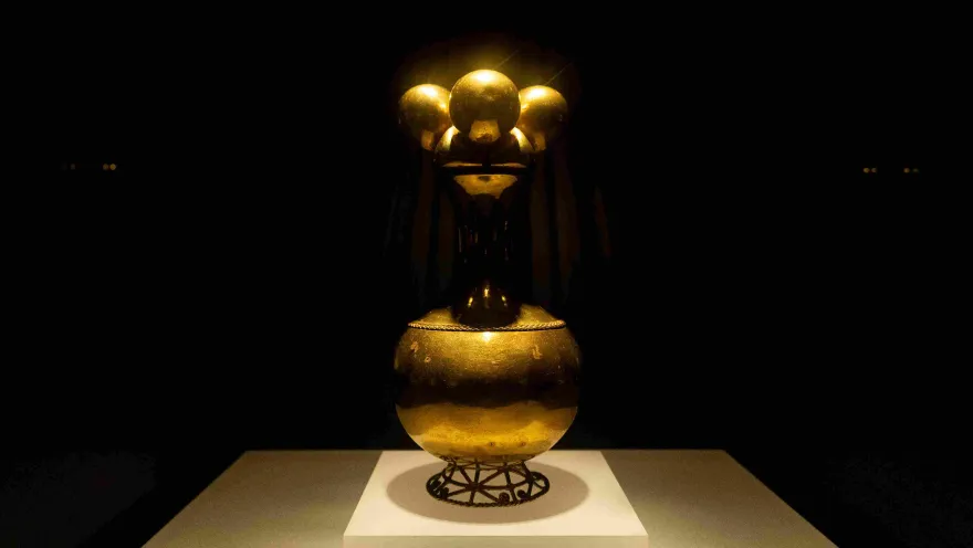 Pieza de Poporo dorado. Una luz desde arriba la ilumina.