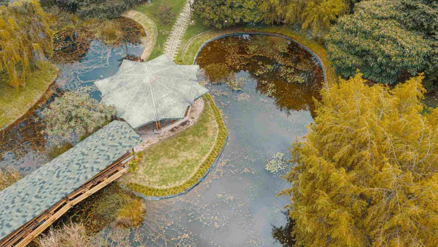 Lake seen from above, surrounded by abundant vegetation. There is a kiosk in the middle.