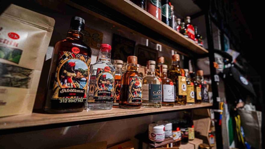 Varias botellas llenas, parece de licor, y ubicadas sobre un estante de metal y de madera.