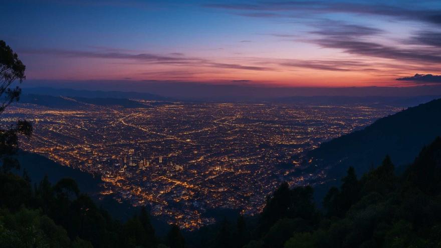  La ciudad iluminada al atardecer desde los cerros orientales. El cielo es rojo y violeta.