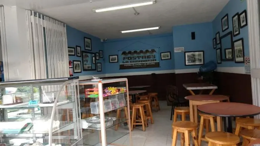 Interior de local comercial donde hay varias vitrinas, mesas y sillas.