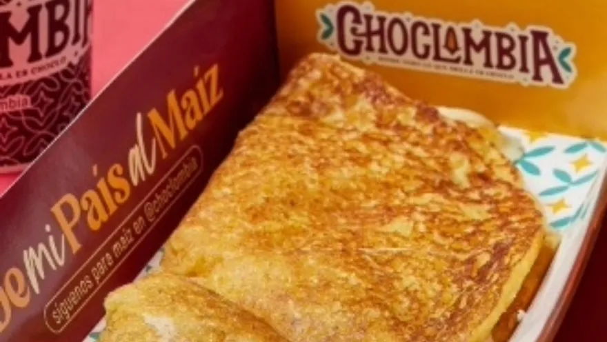  Primer plano de un trozo de pan dorado en una canasta con una leyenda que dice: "Choclombia".