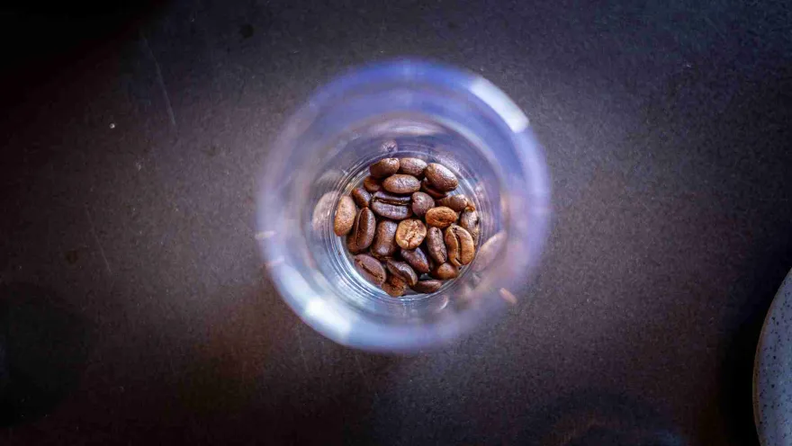 Primer plano de copa de cristal con unos granos de café al interior.