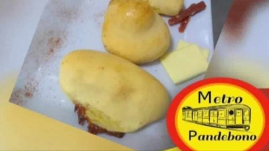  Primer plano de dos amasijos de pan y un letrero con una leyenda que dice: "Metro Pandebono"