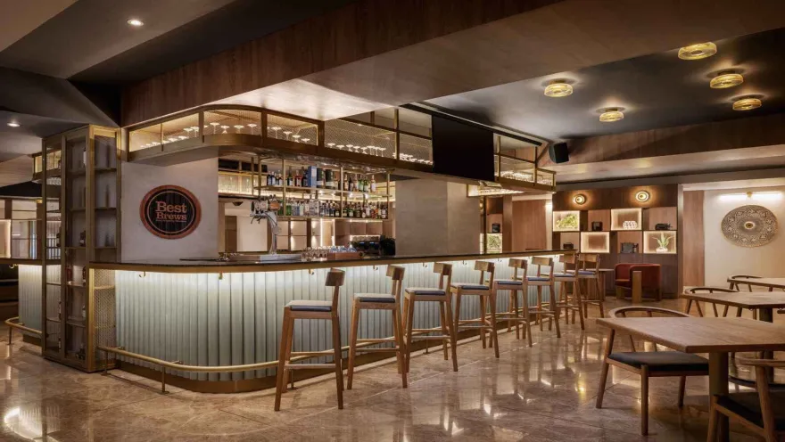  Bar moderno con taburetes, barra retroiluminada y estanterías de copas.