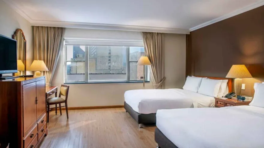 Habitación de hotel con dos camas dobles y escritorio. Una estancia cómoda con vista a la ciudad.