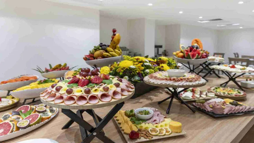  Una mesa de buffet con una abundancia de frutas frescas, embutidos, quesos y otros bocadillos, presentados de forma artística y apetitosa.