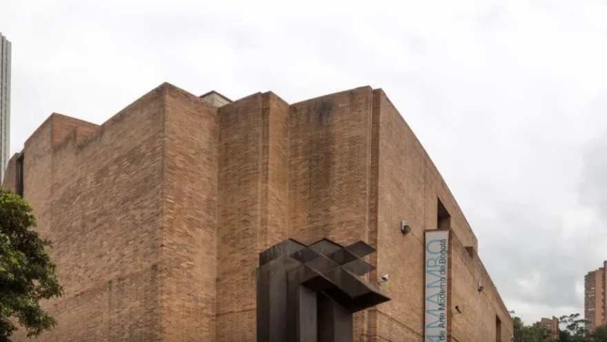 Facade of a large brick building with a prominent sign in blue letters that reads: “MAMBO”.