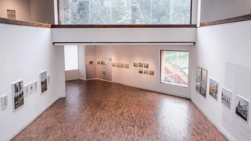 Well-lit, two-story interior room with a large window facing the street and several paintings on the white-painted walls.