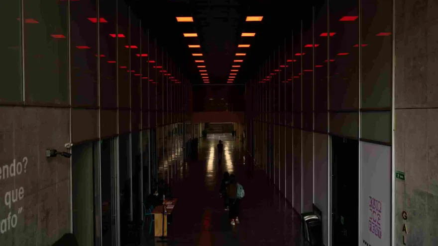 A long, dark interior hallway with offices on either side. A few people are walking around.