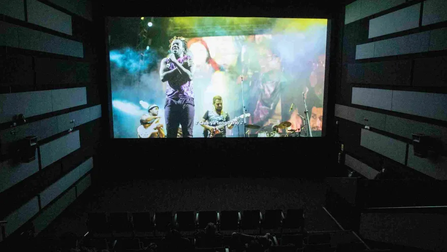 The interior of a movie theater showing a film with a musical performance.