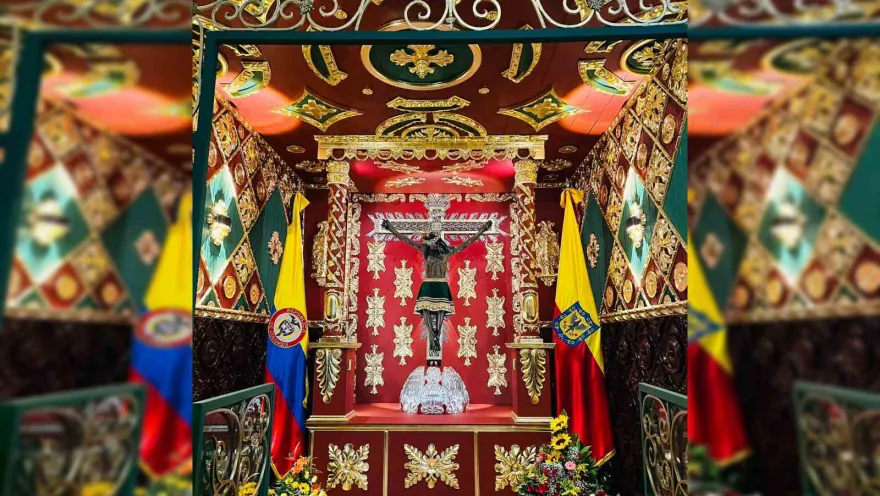 Figure of the so-called ""Lord of Miracles"" in a decorated space surrounded by the flags of Colombia and Bogotá.