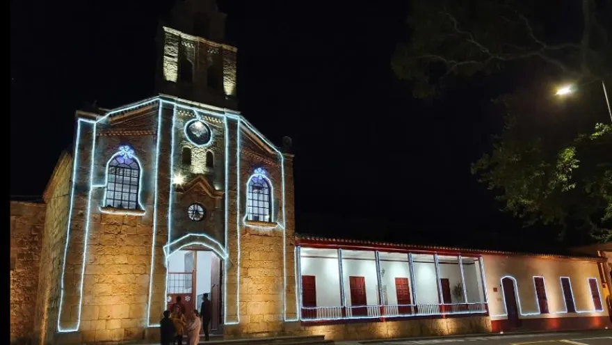 Panoramic view of the parish church's facade at night, adorned with neon lights.