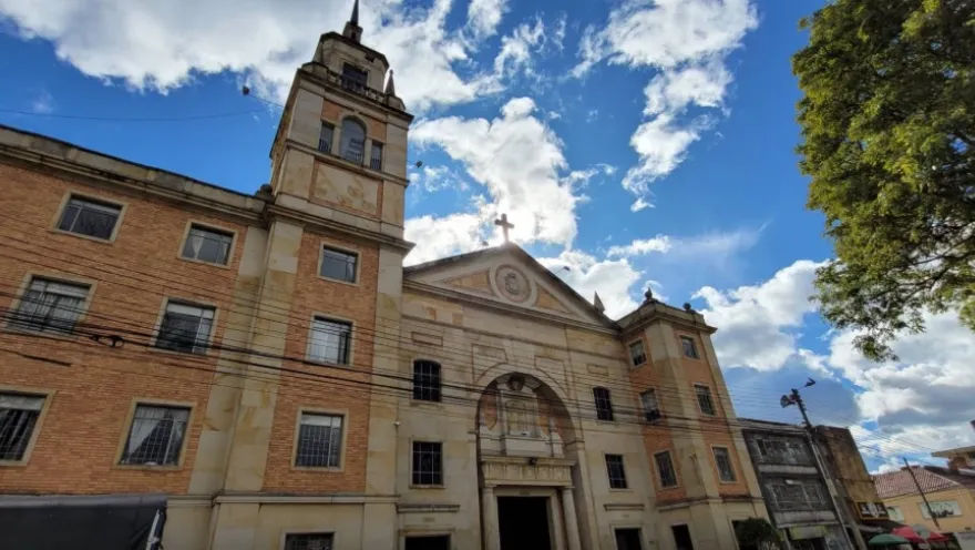 Facade of the San Alfonso parish church in stone and brick. Above, the sky is blue.