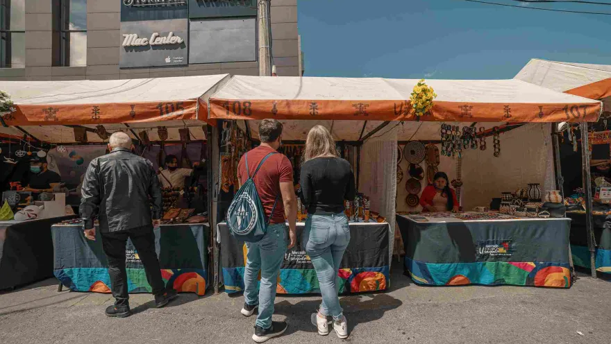 A young man and woman stand in front of a vendor stall, seemingly looking at handicrafts.