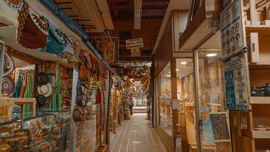 Interior de locales comerciales con coloridos artículos artesanales como sombreros, ruanas y hamacas.