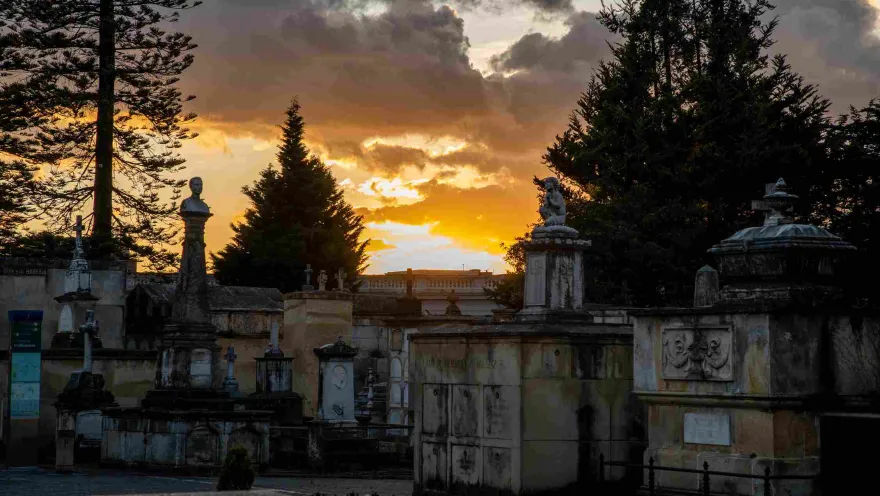 Panoramic view of the interior with stone mausoleums surrounded by trees at sunset.