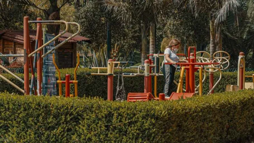 A woman plays on playground equipment, enjoying a sunny and fun day.