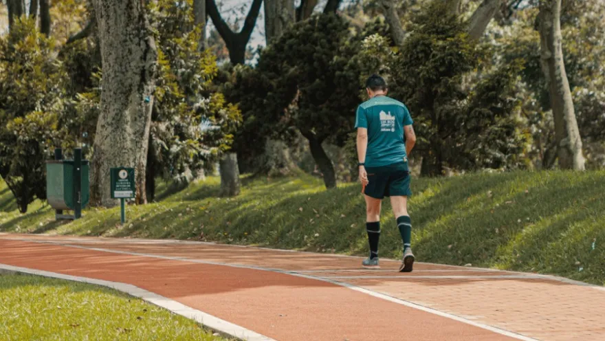 A man walking along a path. Wearing shorts and sneakers, he appears to be exercising.